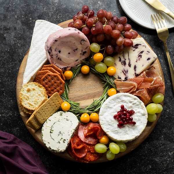 A cheese board with different types of crackers and fruits.